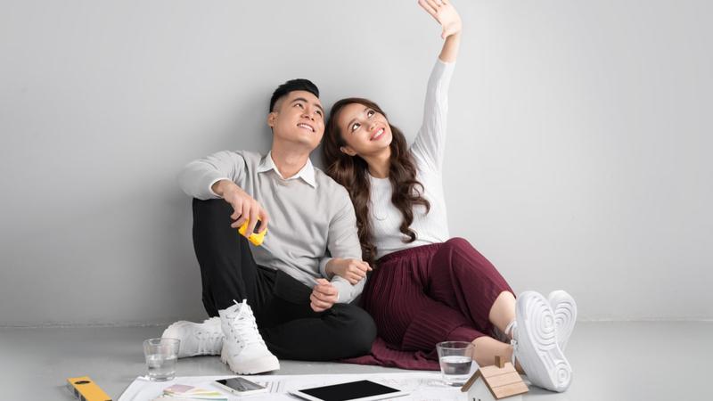 Happy Asian couple dreaming about home renovation