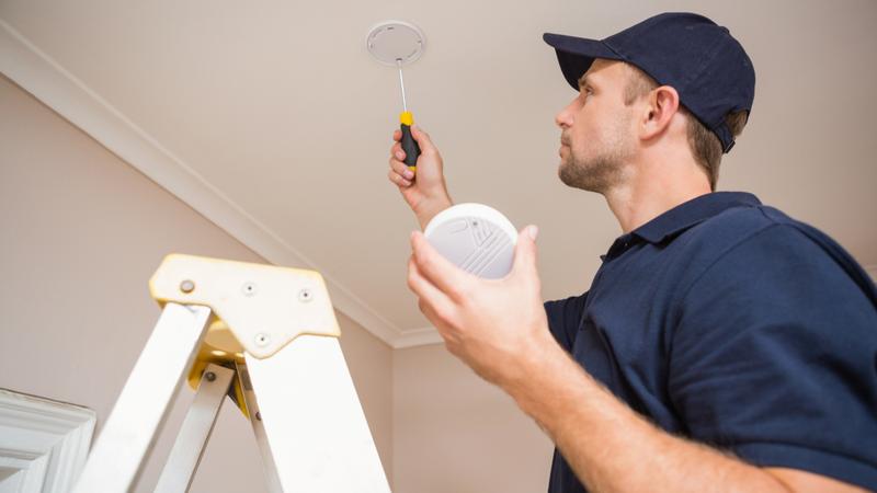 A handyman installs a smoke detector